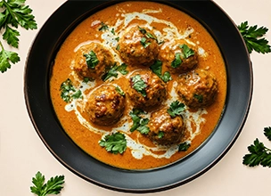 Malai Kofta, a popular North Indian vegetarian specialty consisting of fried dumplings in a rich, creamy tomato-based gravy.